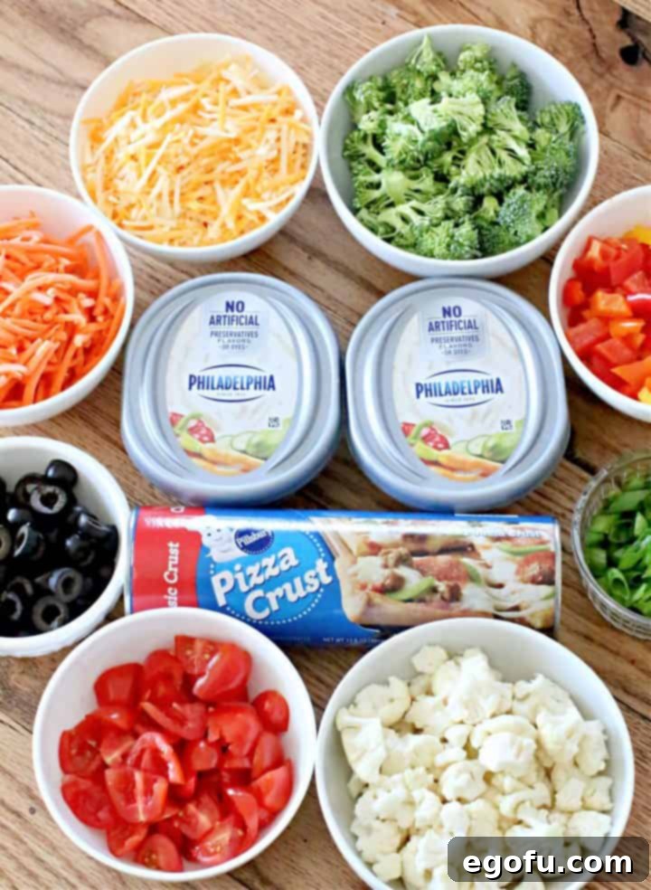 Veggie Pizza Ingredients: refrigerated pizza crust, garden vegetable cream cheese, salt, pepper and garlic powder, chopped broccoli florets, chopped cauliflower florets, shredded carrots, shredded colby jack cheese, diced bell peppers, diced tomatoes, sliced olives, sliced green onion