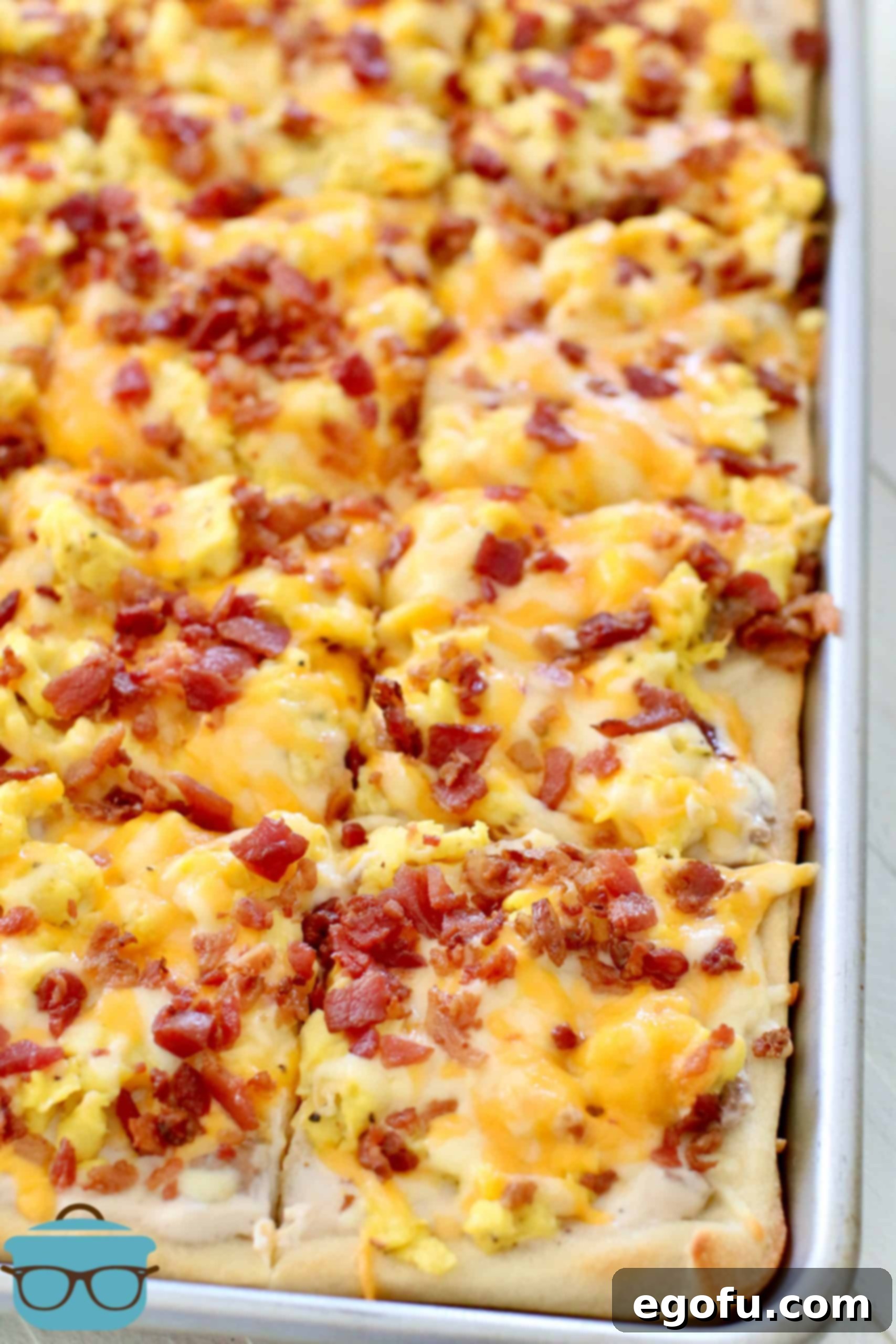 Morning Masterpiece Pizza 2 Fully cooked Breakfast Pizza shown sliced into squares in baking pan.