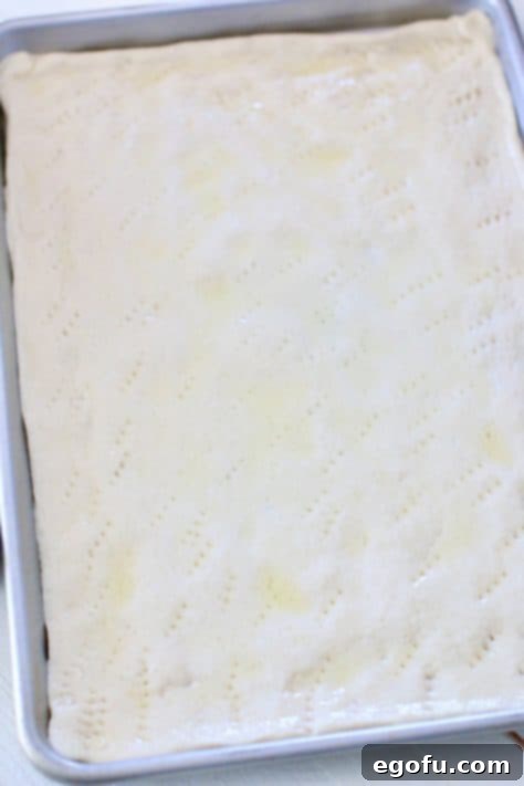 Morning Masterpiece Pizza 12 pizza dough spread out on a rectangle baking sheet