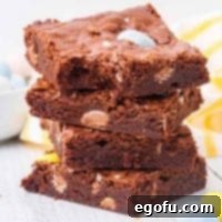 Fudgy Easter Egg Brownie Delights 9 Close up of Stacked Easter Egg Brownies with a bite taken out of one, showcasing its fudgy interior and mini Cadbury eggs.