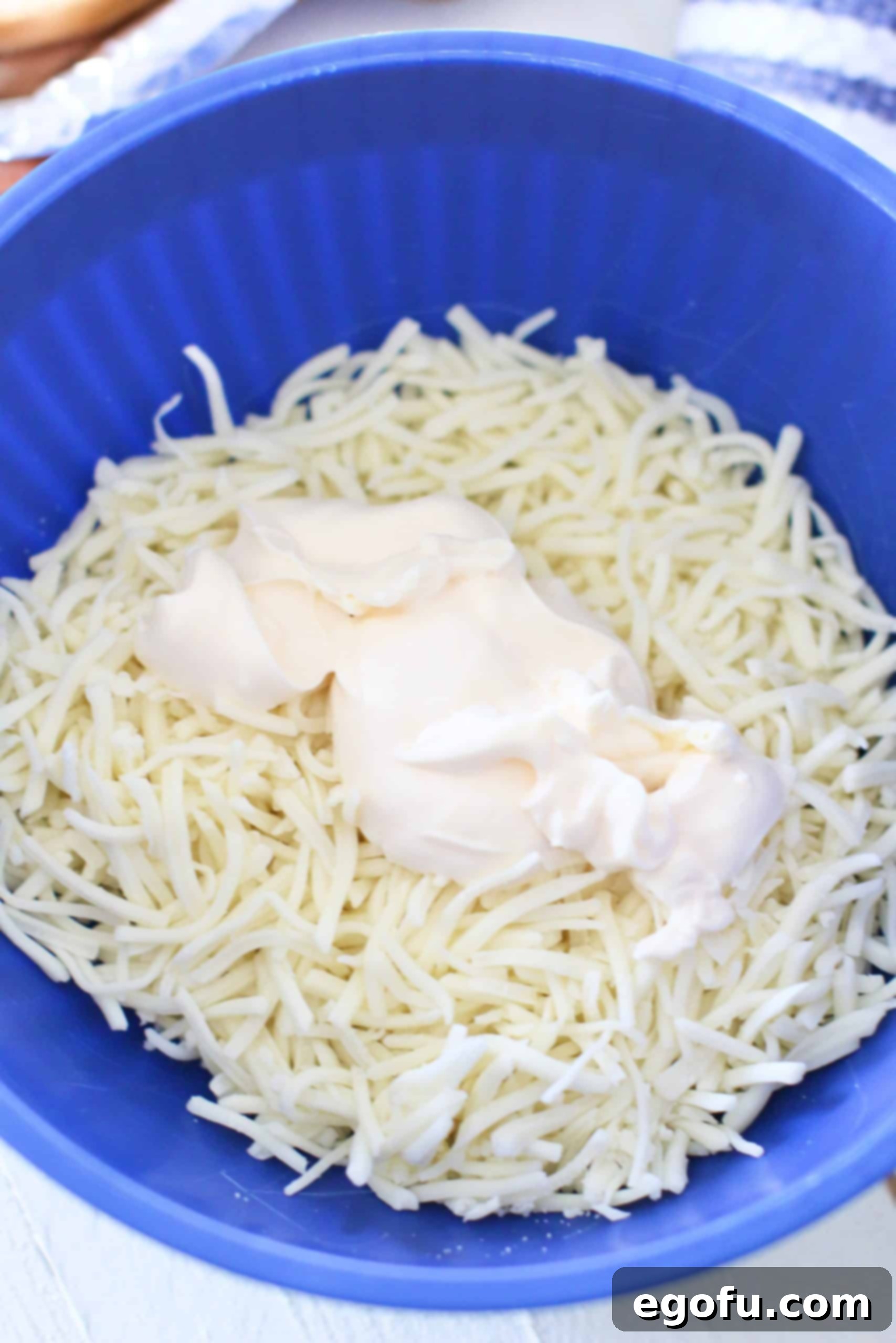 mayonnaise and shredded mozzarella cheese shown in a blue bowl.