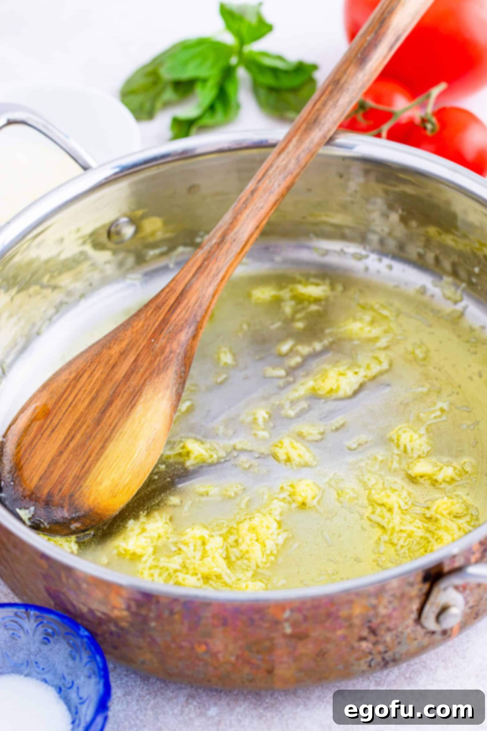 From Scratch Pizza Sauce Perfection 5 Golden olive oil shimmering in a large skillet with finely minced fresh garlic sizzling, releasing its aromatic fragrance as it gently sautés.