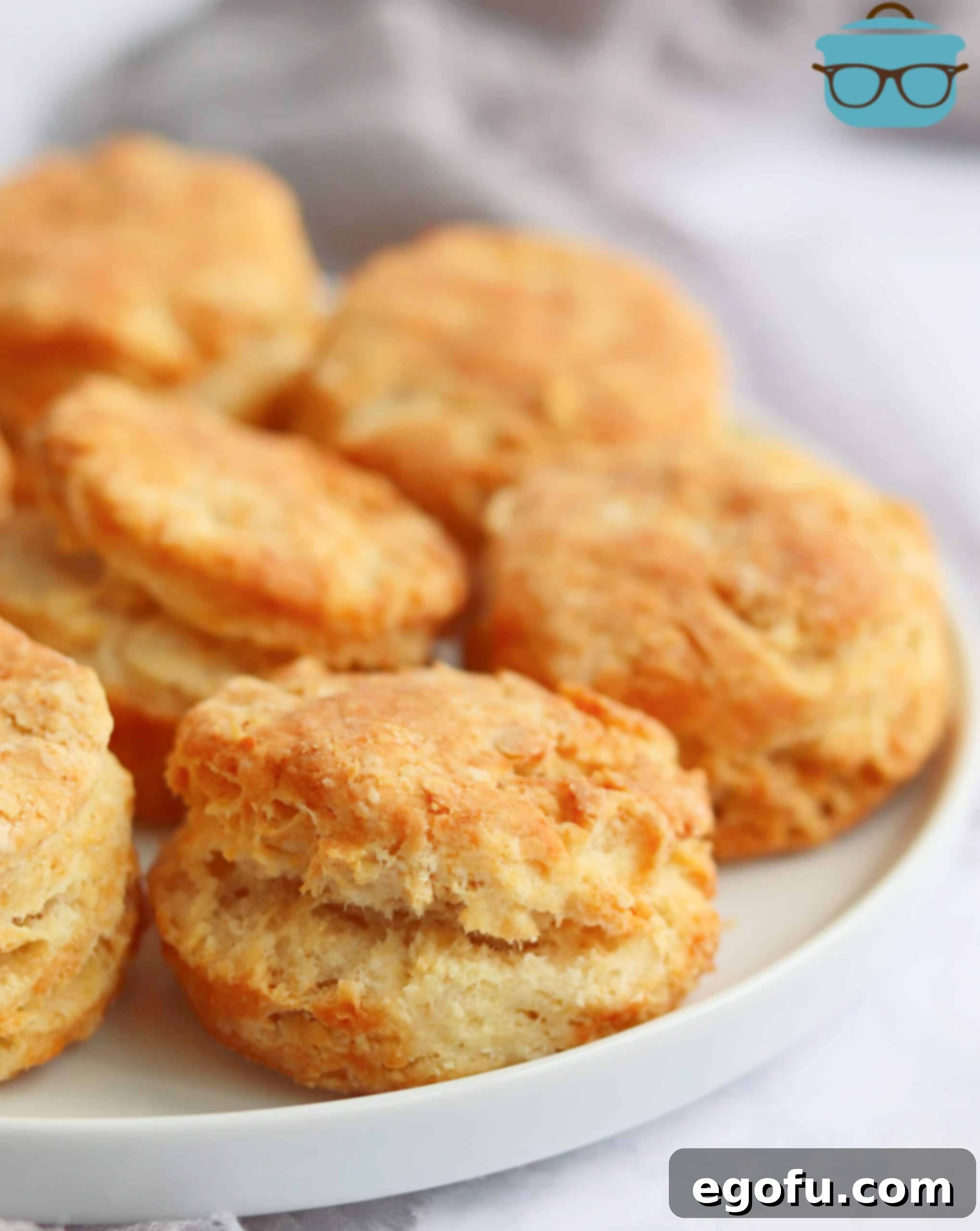 A close-up shot of freshly air-fried buttermilk biscuits on a white plate, revealing their flaky layers and golden crust, inviting a taste.