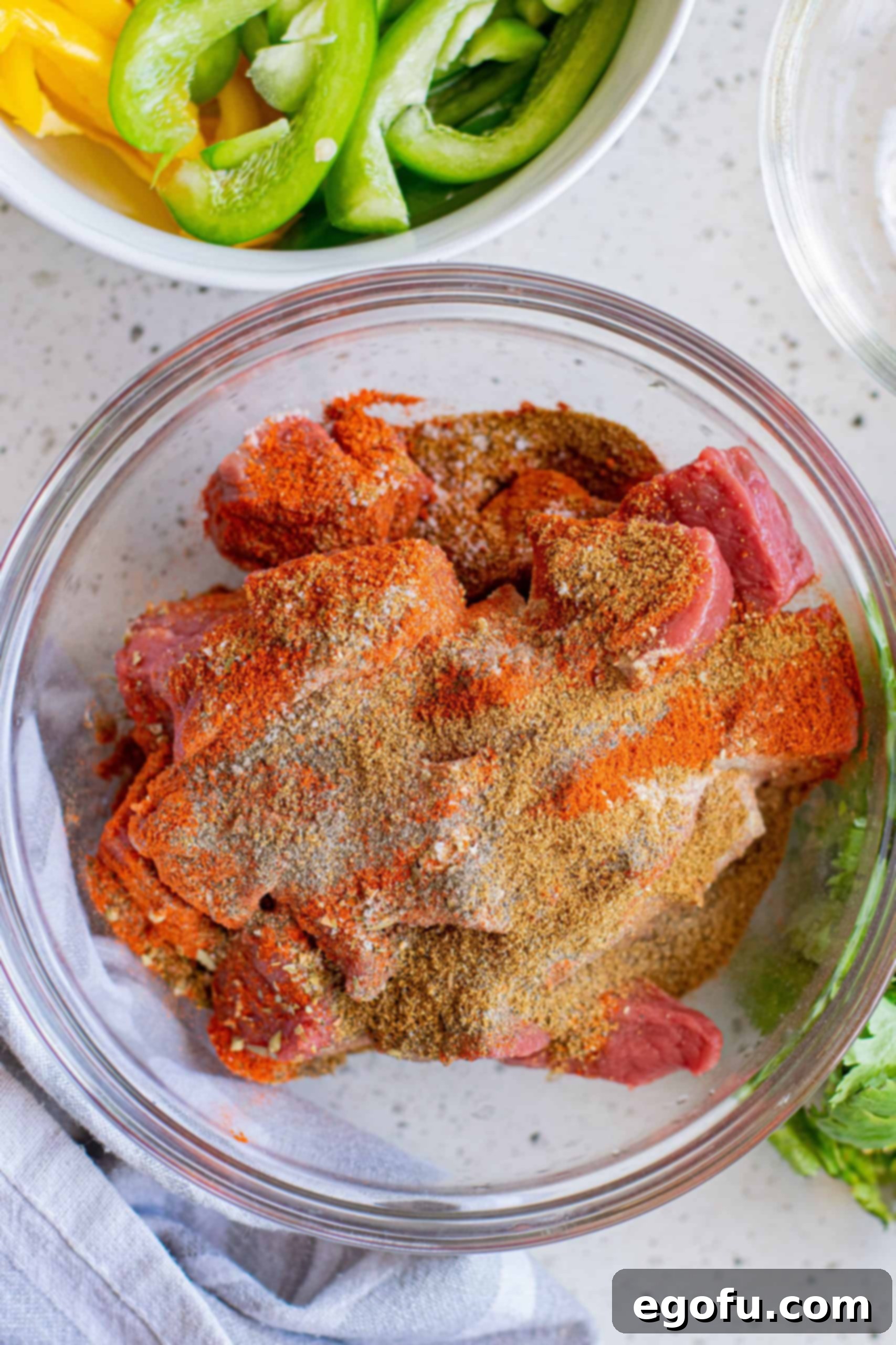 Seasonings sprinkled over steak bites in bowl.