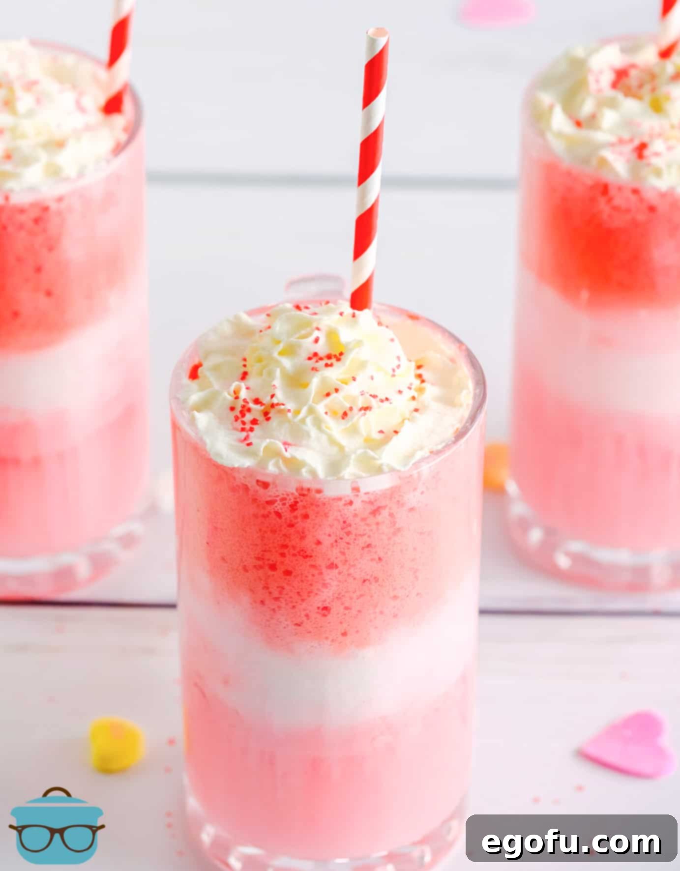 Close up of Strawberry Cream Floats in glass topped with whipped cream, sprinkles and a straw.