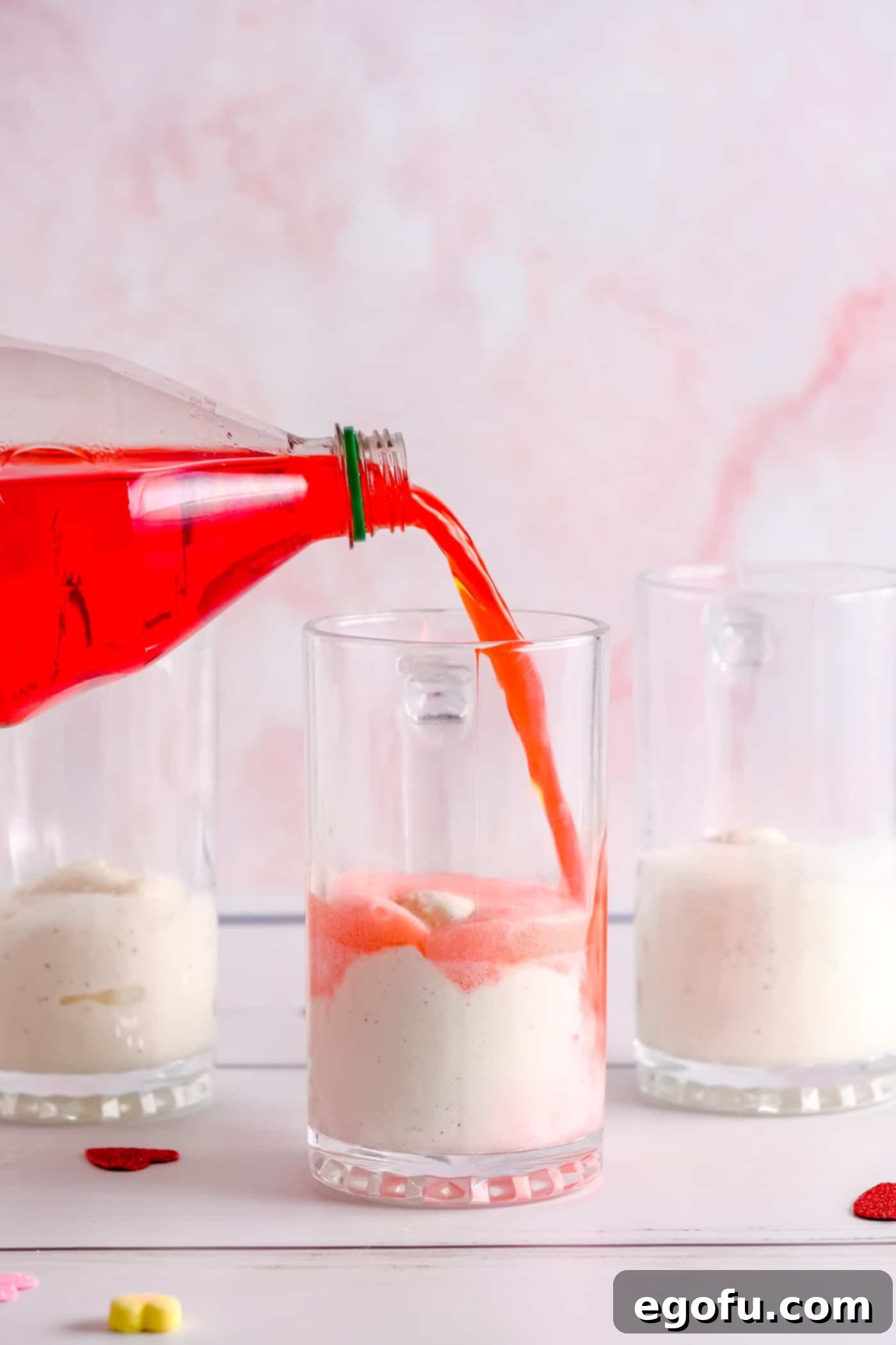 Soda being poured over ice cream in glass.