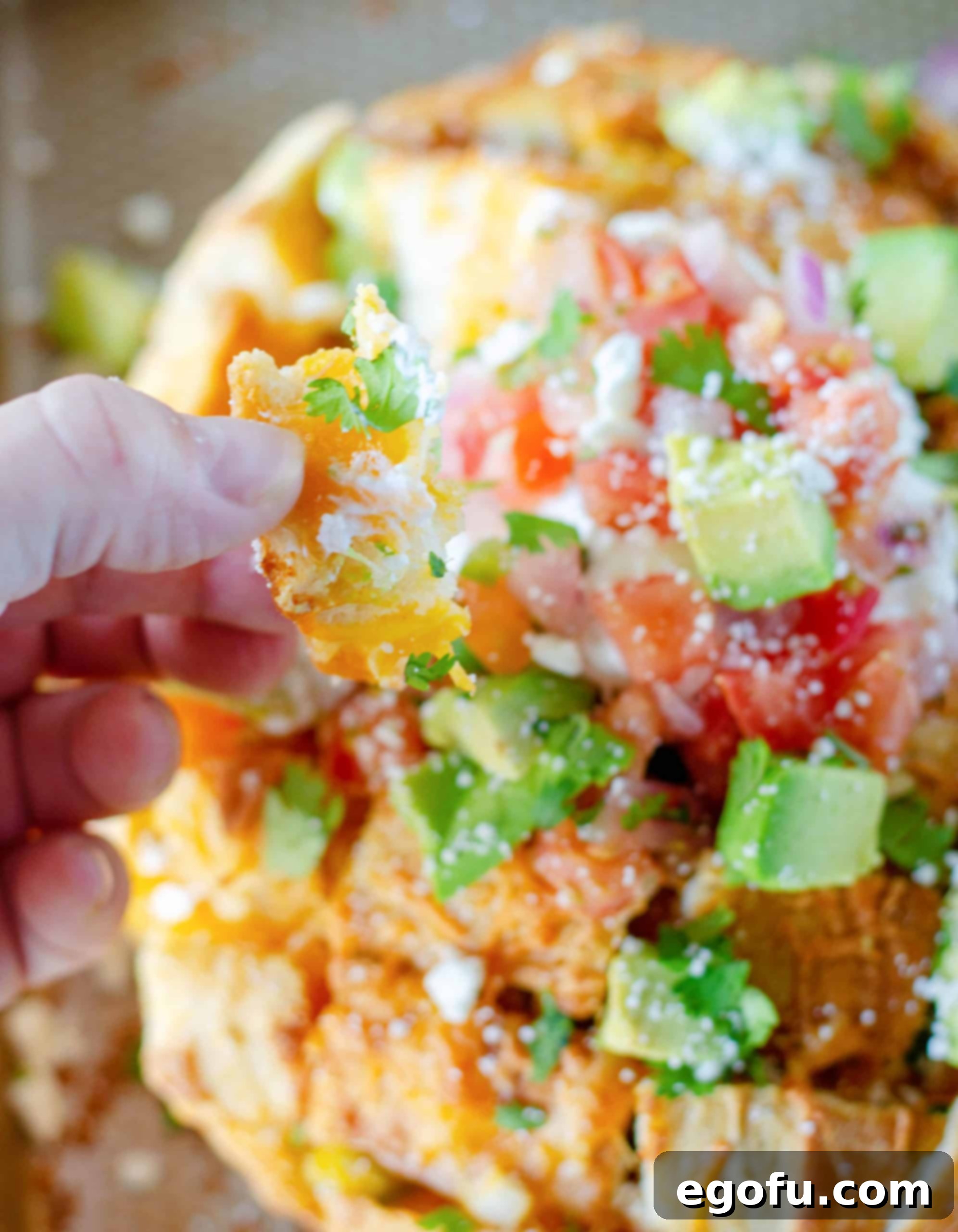 A hand pulling a delicious piece of Taco Pull Apart Bread from the loaf, highlighting its interactive and appetizing nature.