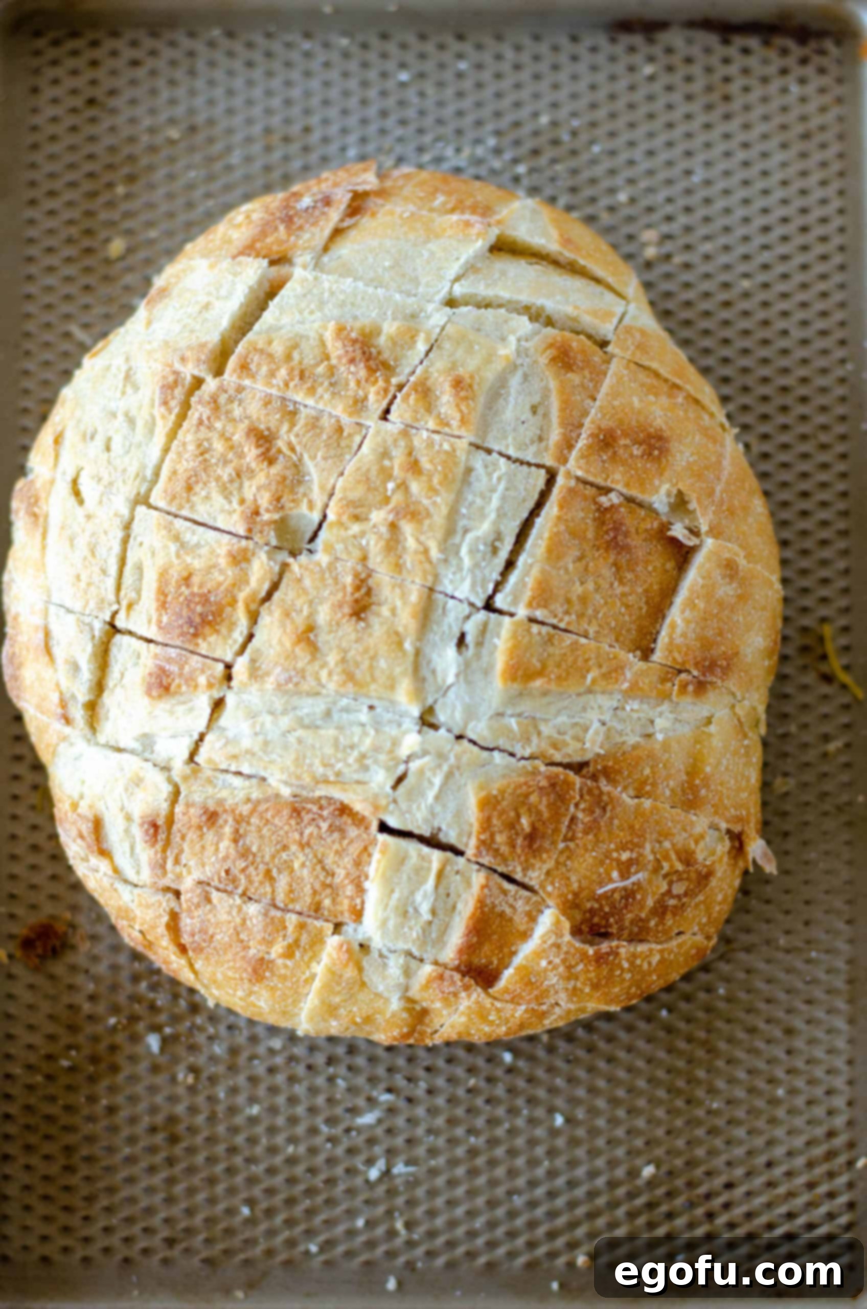 Bread on baking sheet with two sets of diagonal cuts, showing the completed grid pattern ready for filling.