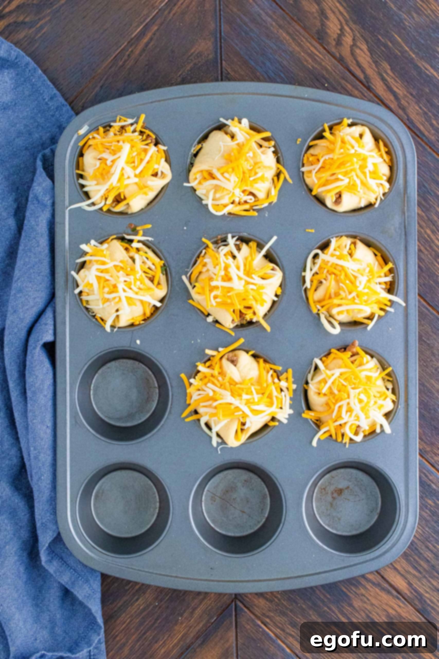 More cheese added to wrapped Taco Cups in muffin tin before baking.
