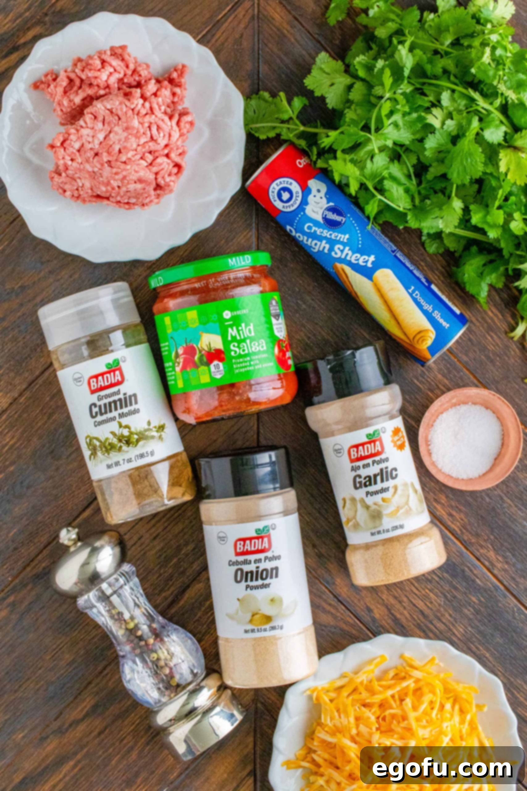 Ingredients needed: lean ground beef, ground cumin, garlic powder, onion powder, kosher salt, black pepper, salsa, water, cilantro, crescent roll dough sheet and shredded Colby jack cheese arranged for cooking.