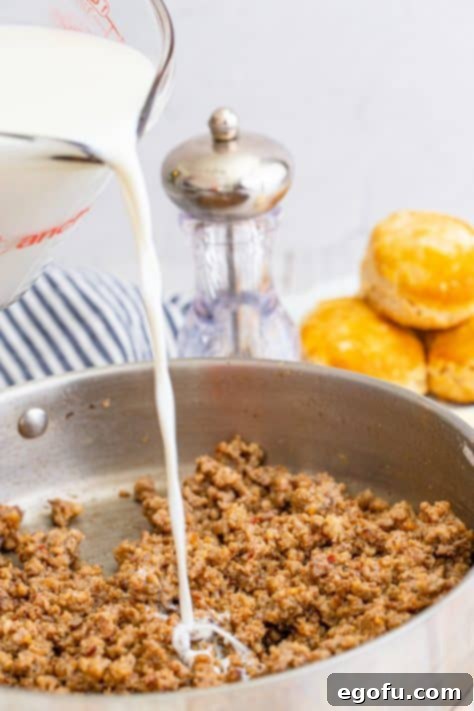 Milk being poured into cooked sausage in metal pan