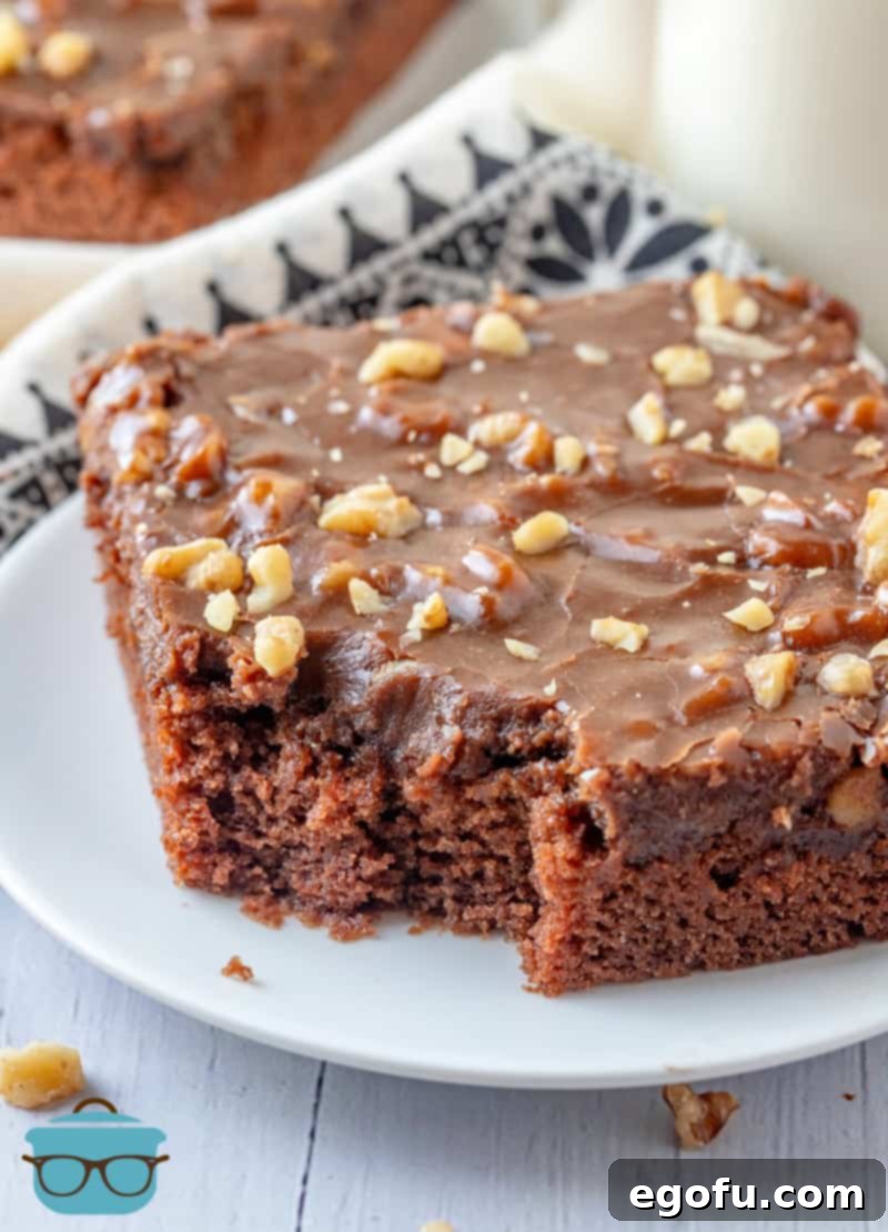 Slice of Grandma's Sheet Cake on white plate with bite taken out.