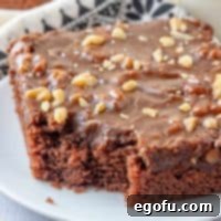 Square image close up of Grandma's Texas Sheet Cake on white plate with bite taken out
