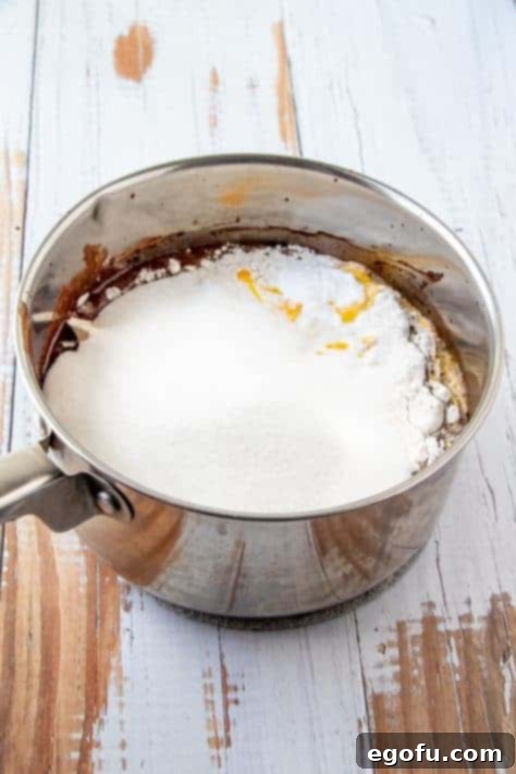 Flour, eggs, baking soda, sugar and sour cream added to melted chocolate mixture in metal sauce pan