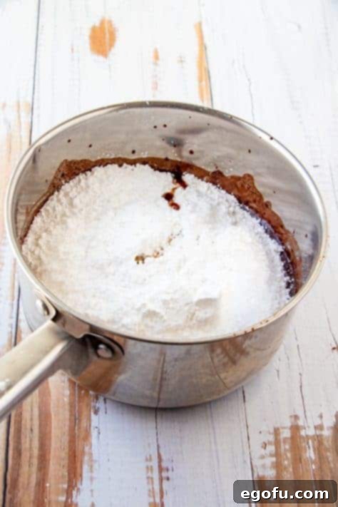 Nuts, powdered sugar and vanilla added to cocoa mixture in metal sauce pan