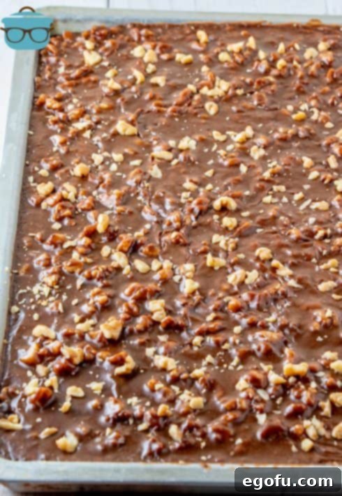 Frosting poured over top of cake and topped with more nuts