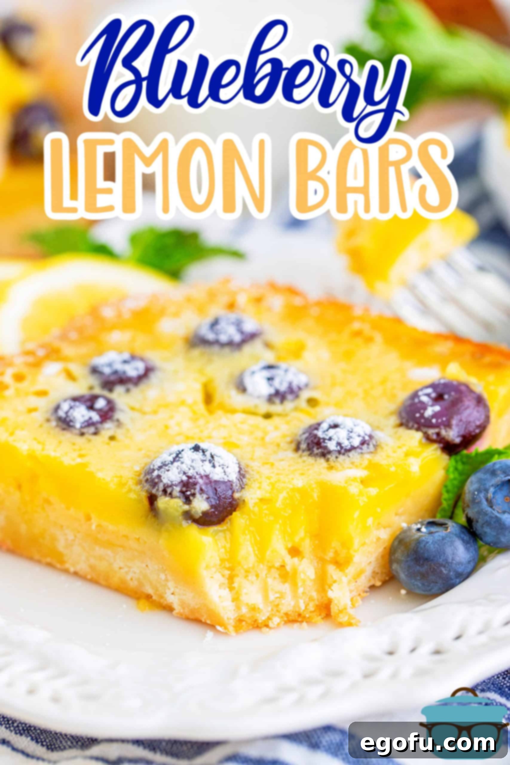 Close-up of a Blueberry Lemon bar with a bite taken out, showing the rich texture and blueberries, served on a white plate.
