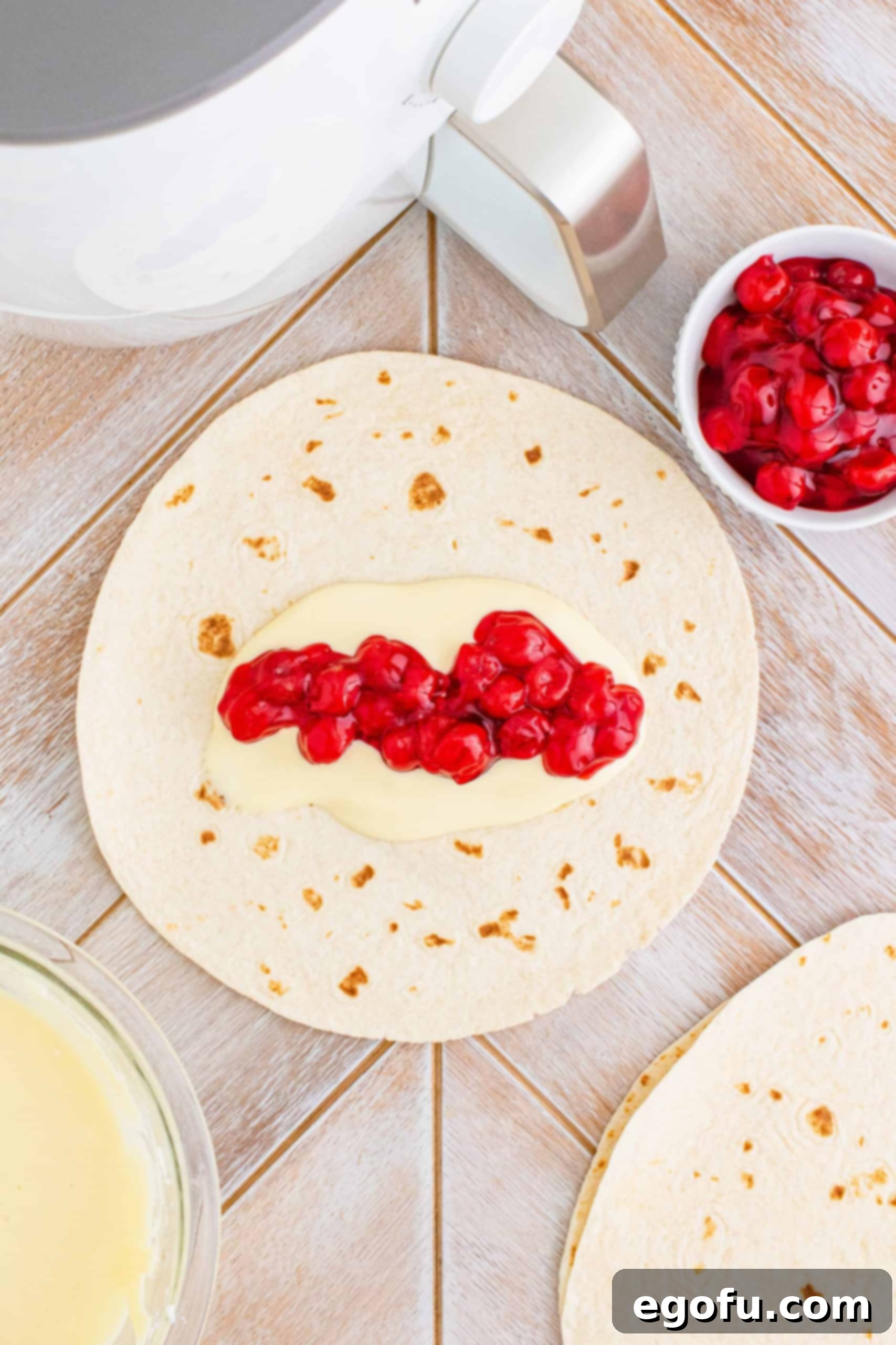 Cherry pie filling spread on top of cheesecake filling on tortilla. 
