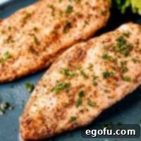 Close-up of golden brown Air Fryer Chicken Breasts garnished with parsley on a gray plate.