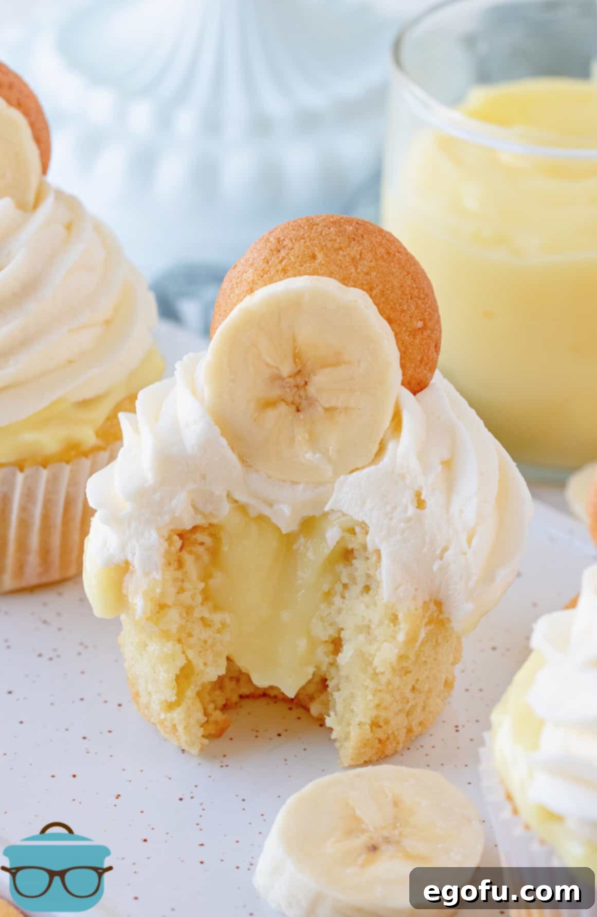 Velvet Banana Delight Cupcakes 2 A delicious Banana Pudding Cupcake with a bite taken out, showcasing the creamy banana pudding filling inside.
