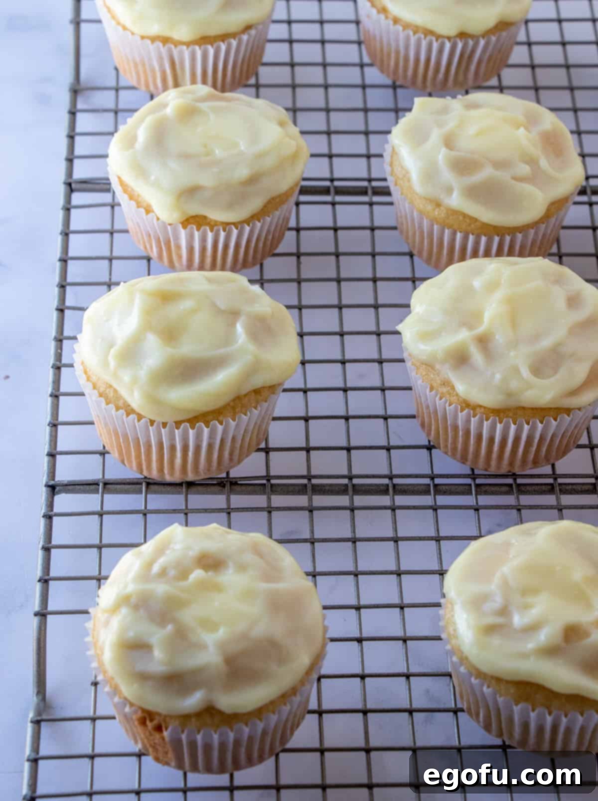 Velvet Banana Delight Cupcakes 19 Cupcakes on a wire rack, filled with banana pudding and a thin layer spread over the tops.