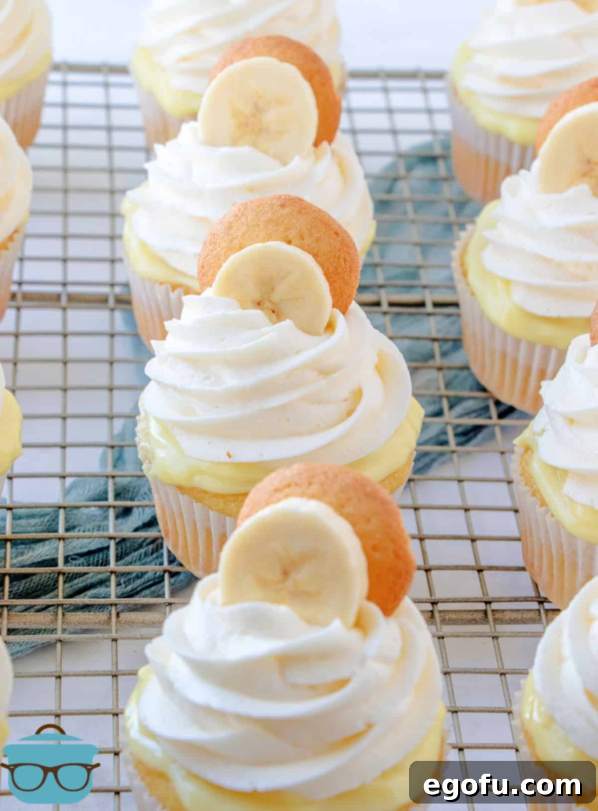 Velvet Banana Delight Cupcakes 20 Finished Banana Pudding Cupcakes on a wire rack, beautifully frosted and garnished with a vanilla wafer and banana slice.