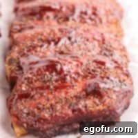 Slow-Smoked Beef Ribs 11 Square image of finished Smoked Beef Ribs uncut on parchment paper with BBQ Sauce