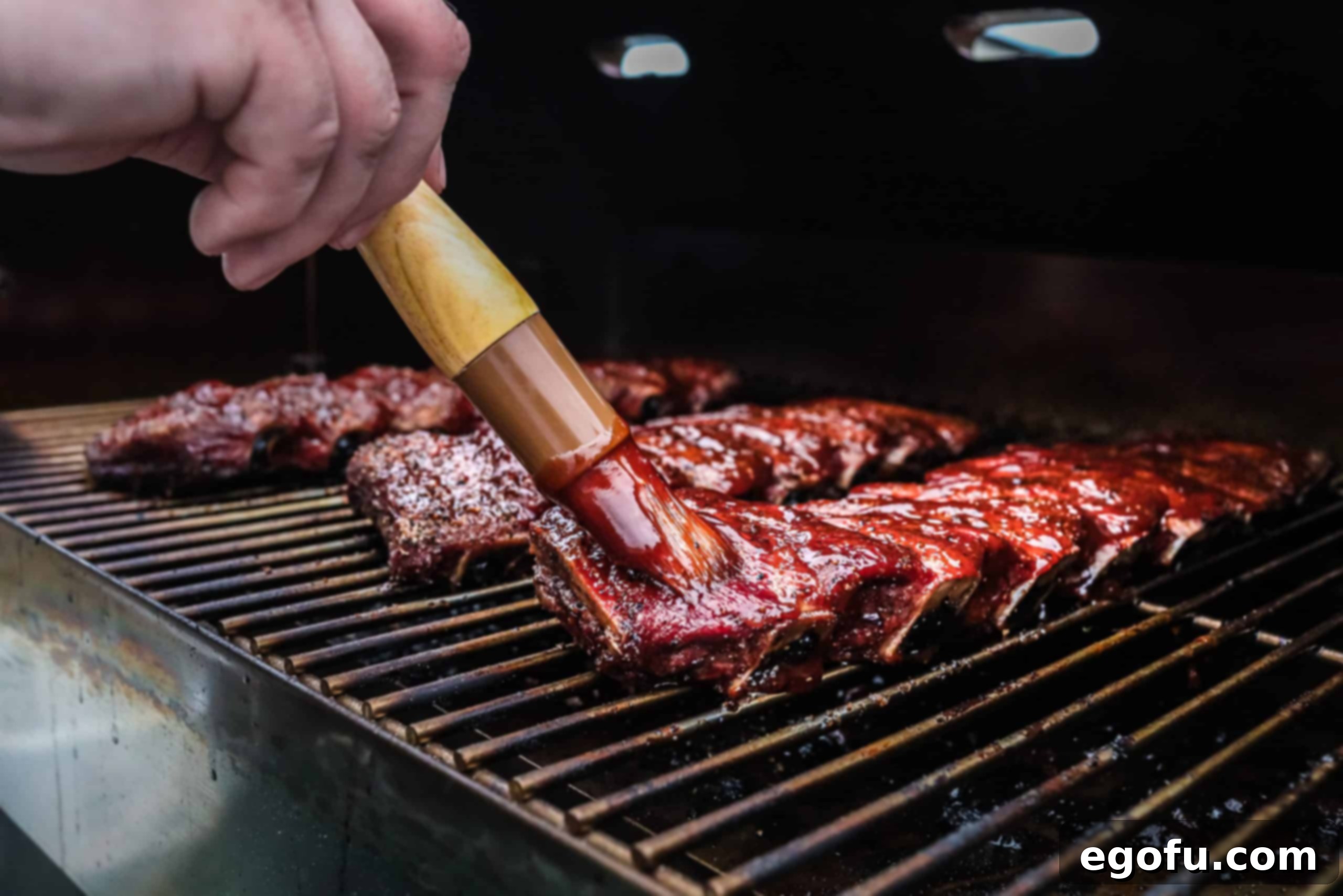 Slow-Smoked Beef Ribs 7 Ribs being brushed with BBQ sauce on smoker.