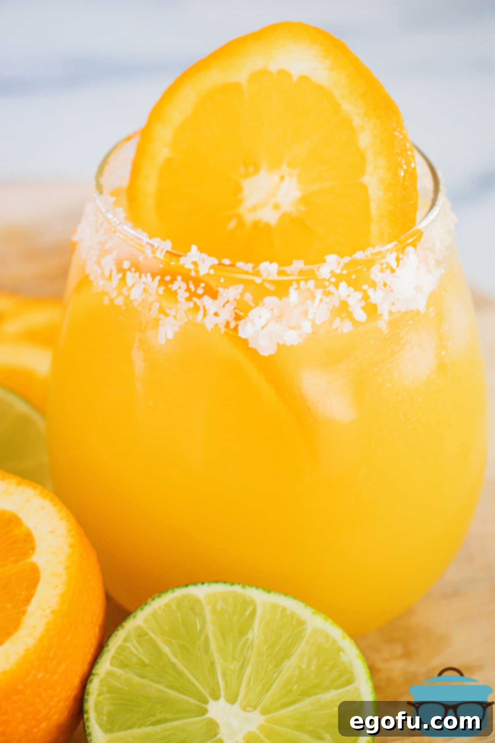 Salt lining the rim of the Orange Margaritas in glass with orange slices.