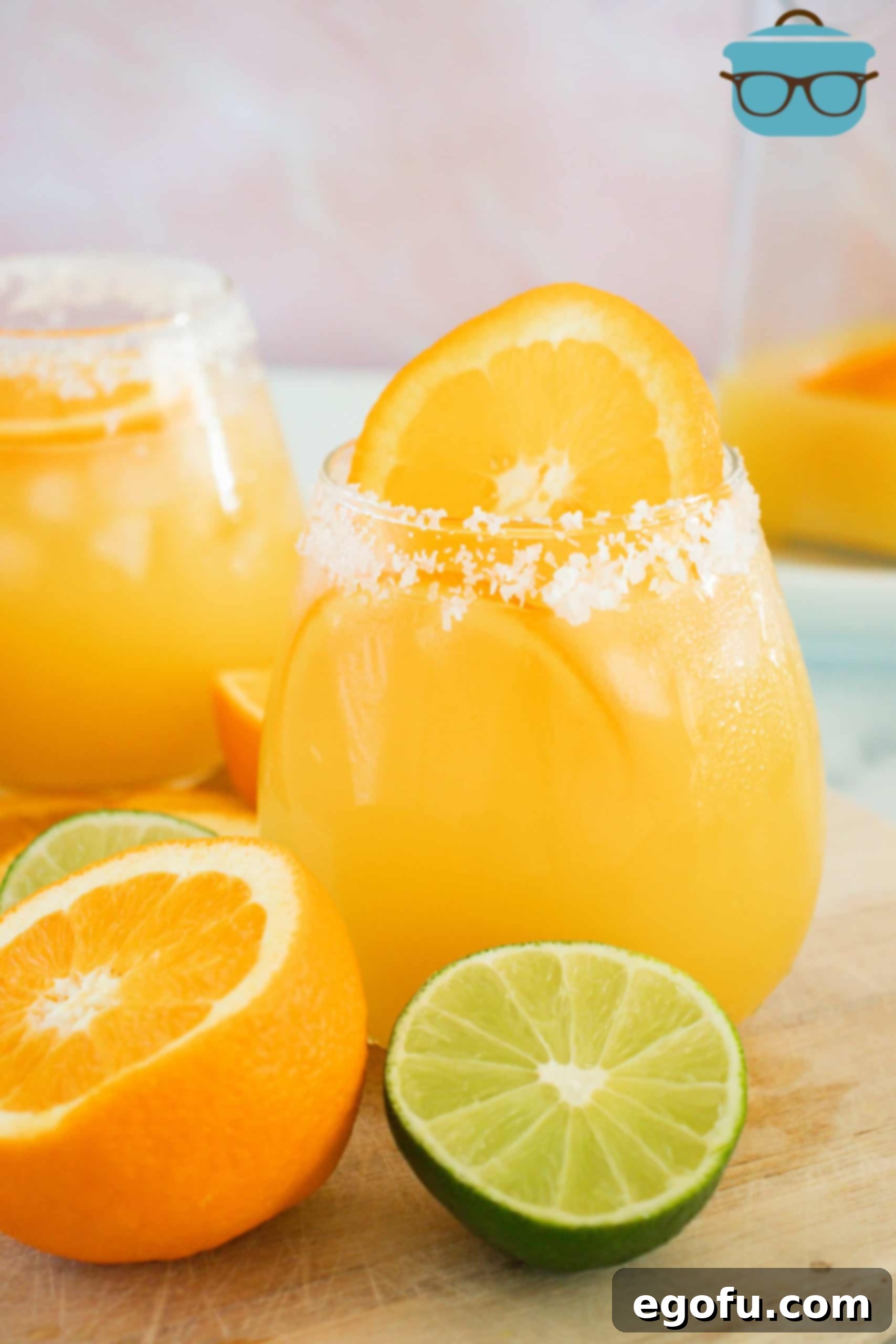 Orange Margarita Recipe in glass with salt rim orange slice and lime next to glass.
