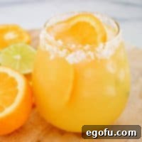Close up square image of finished Margarita in glass with salt rim and orange slice