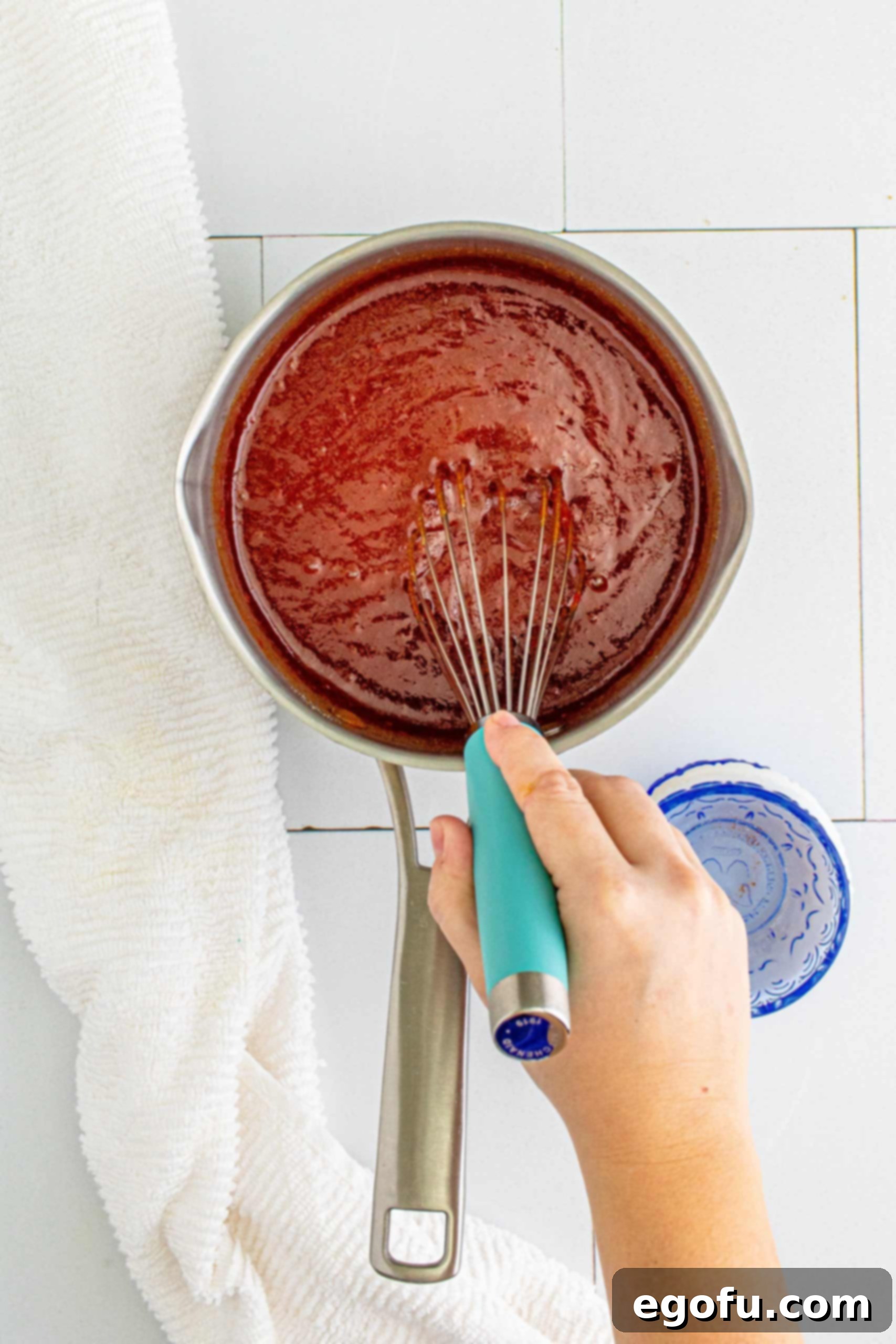 Hand whisking ingredients together in metal saucepan