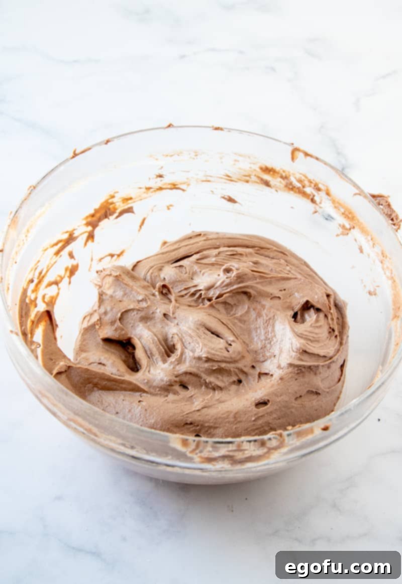 The smoothly beaten M&M Brownie Batter mixture in a clear bowl, showing its creamy texture.