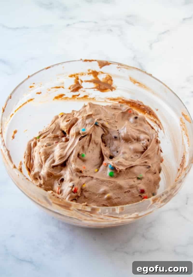 The finished M&M Brownie Batter Dip, with M&M's evenly distributed, presented in a clear bowl.