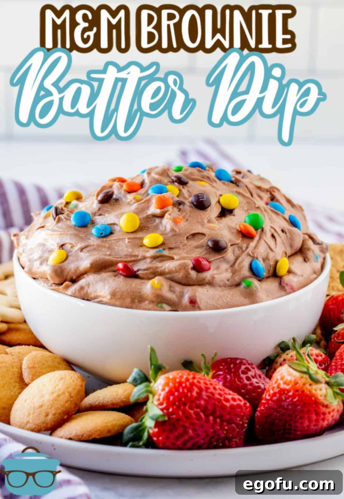 White bowl of M&M Brownie Batter Dip on platter with a variety of fruit and cookies, perfect for Pinterest.