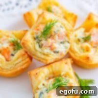 Square photo of Smoked Salmon Puff Pastry Bites stacked on white plate