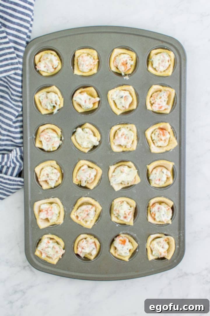 An overhead view of the mini muffin tin with puff pastry cups generously filled with the smoked salmon mixture.