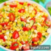 Close-up square image of a white bowl filled with vibrant summer corn salad