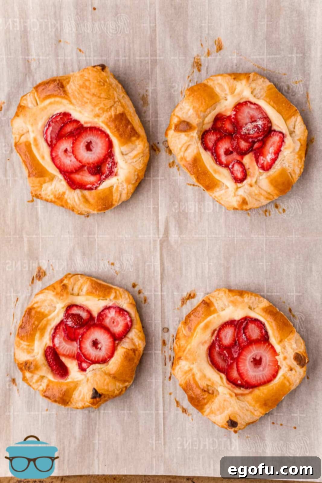 Freshly baked Strawberry Cheese Danishes, golden and delicious, cooling on parchment paper after coming out of the oven.