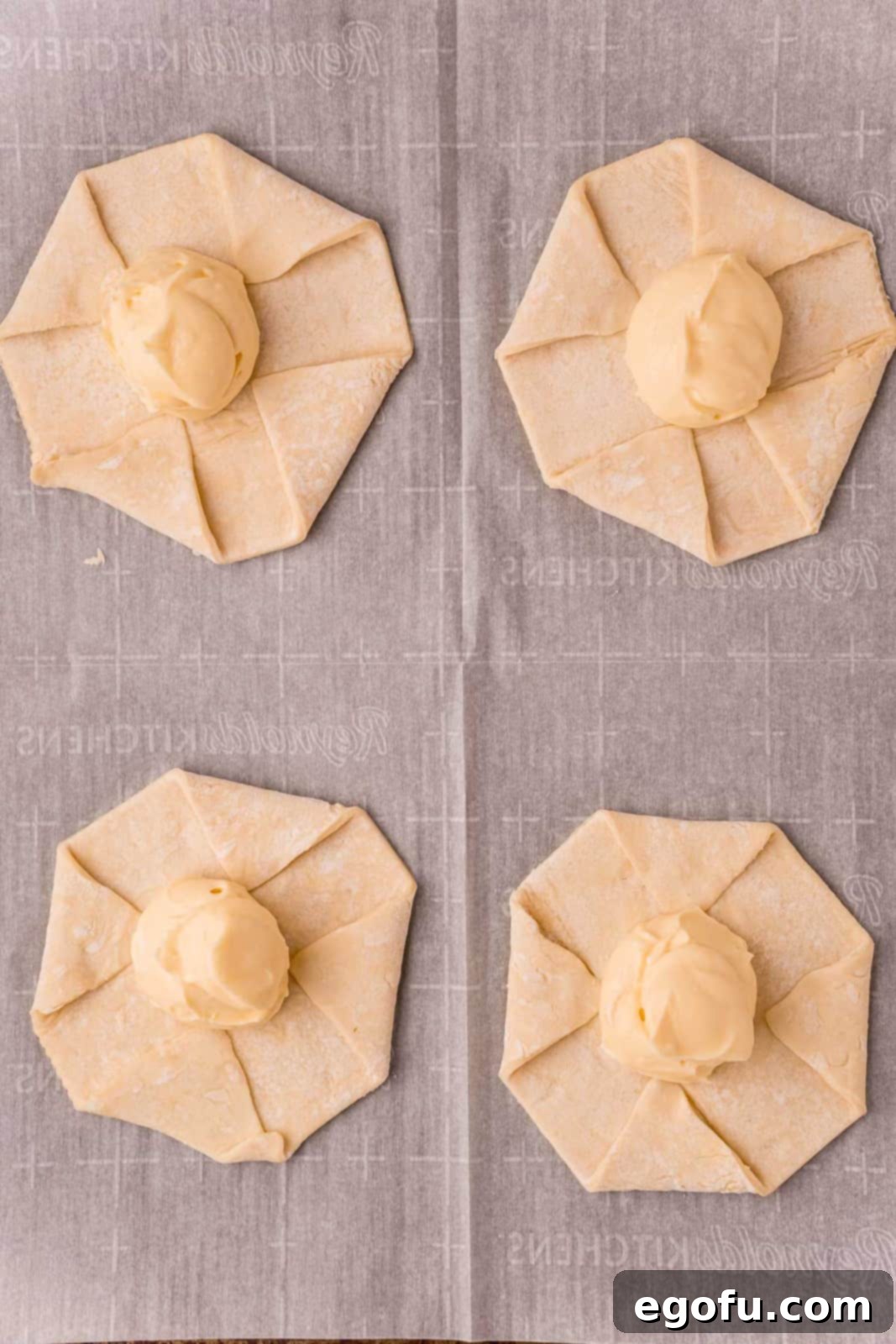 Puff pastry dough, expertly shaped into octagons, topped with dollops of the creamy cheese mixture in the center, awaiting the next steps.