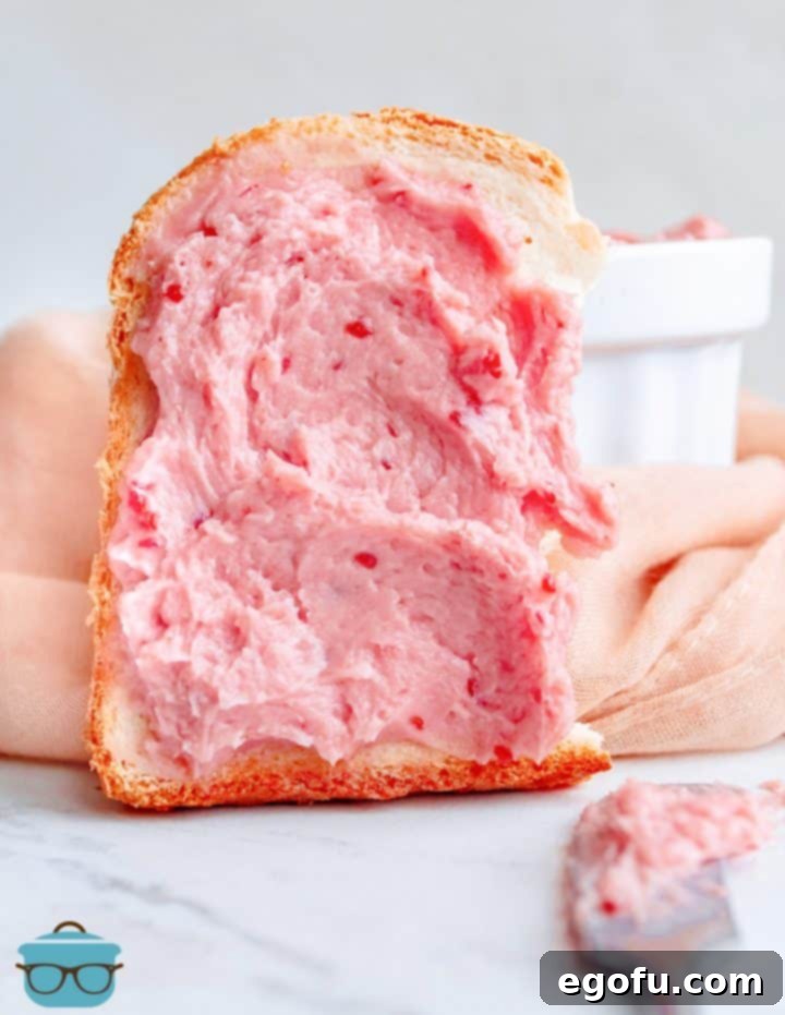 Raspberry Honey Butter generously spread on a piece of toasted bread, ready to be enjoyed.