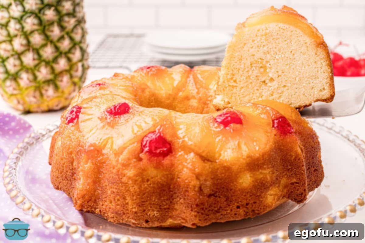 Sunshine Pineapple Bundt Cake 2 Beautifully sliced Pineapple Upside Down Bundt Cake on a serving platter, showcasing its moist texture and vibrant pineapple and cherry topping.
