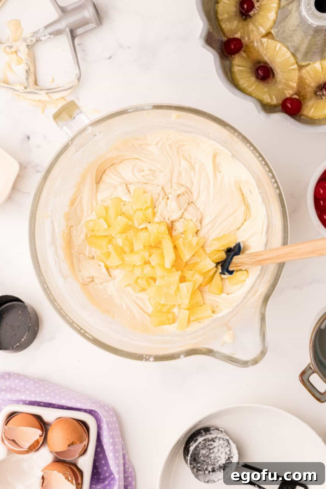 Sunshine Pineapple Bundt Cake 13 Chopped pineapple pieces being gently folded into the cake batter with a spatula.