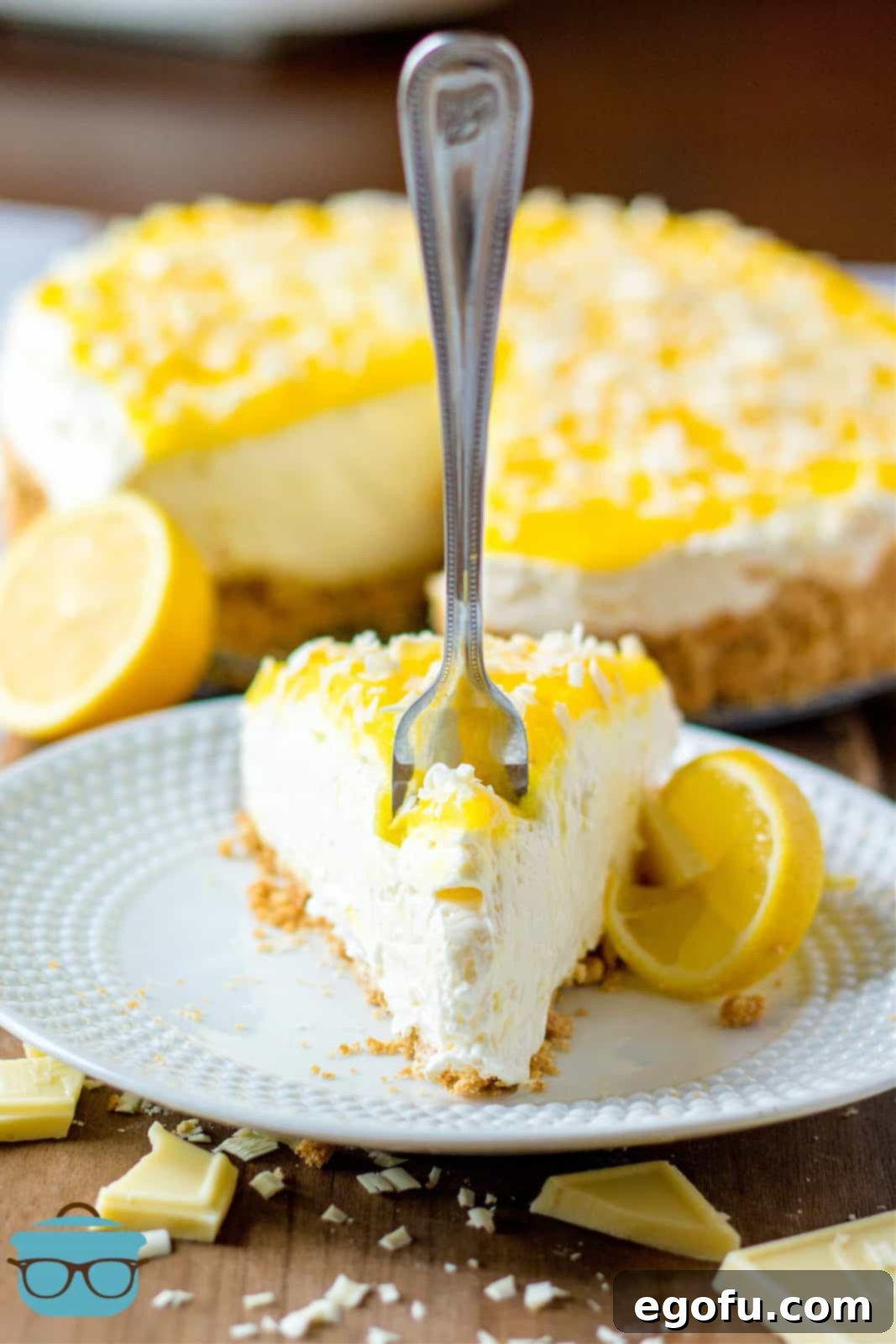 Slice of Cheesecake on white plate with fork sticking into it.