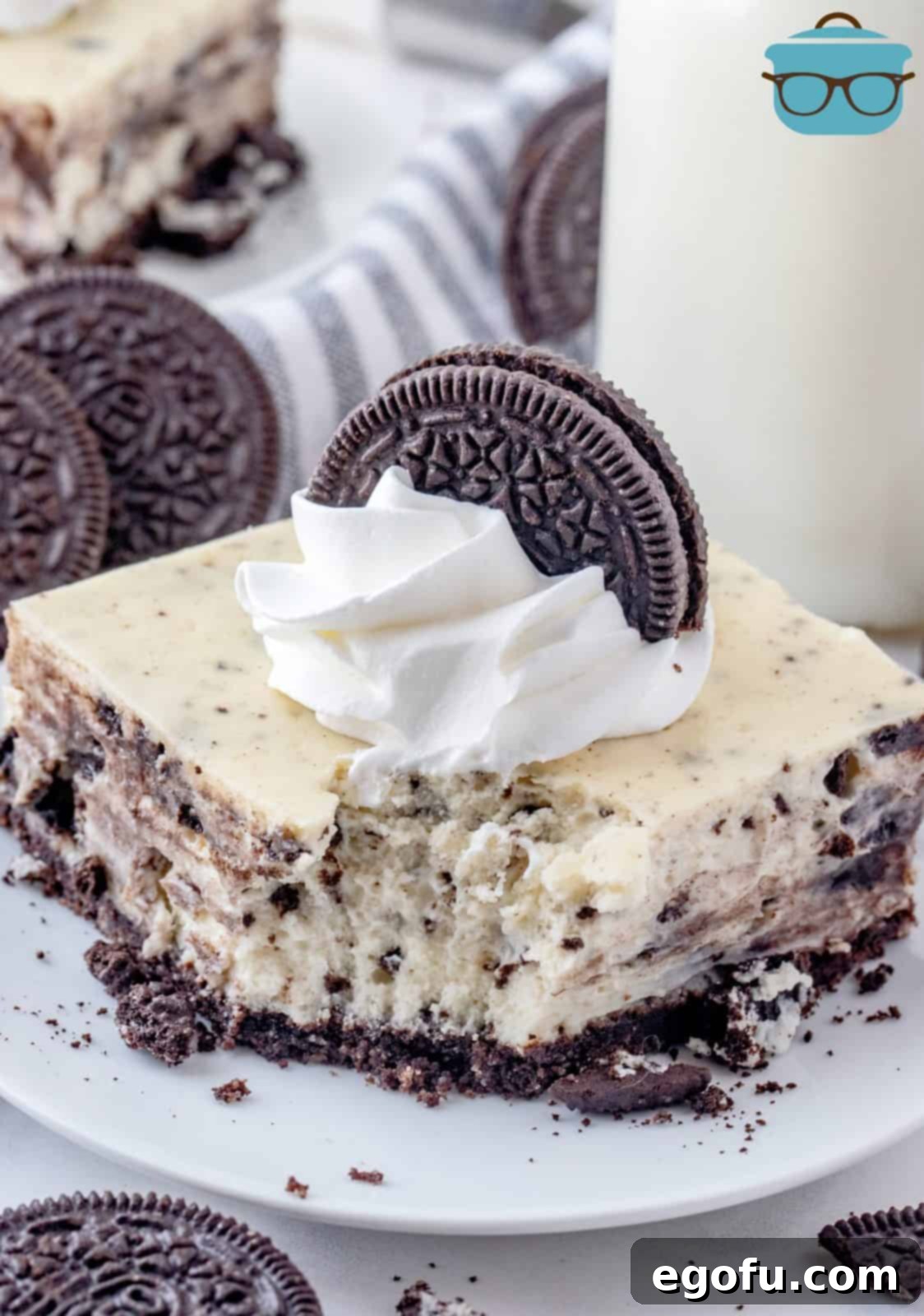 One Oreo Cheesecake Bar on plate with bite taken out, showing creamy filling and cookie chunks.