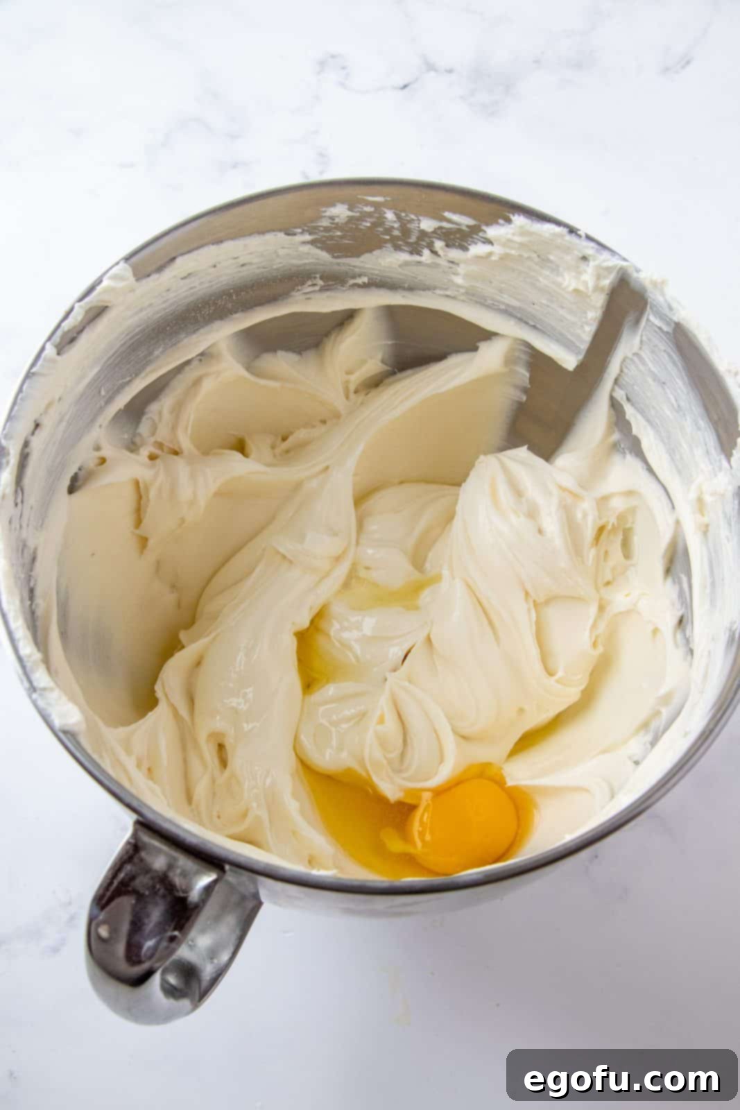 Eggs added to cream cheese mixture in mixing bowl.