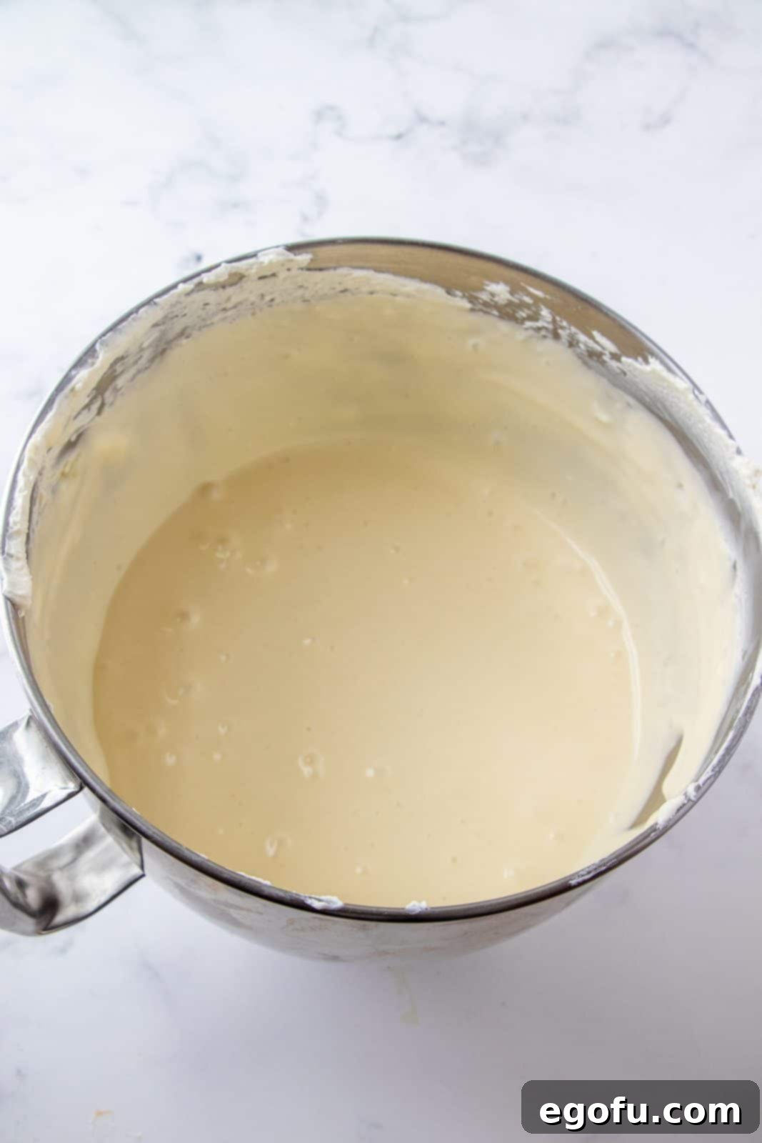 Eggs beaten into cream cheese mixture in mixing bowl.