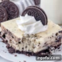 Square image of bite taken out of one of the Oreo Cheesecake Bars on white plate