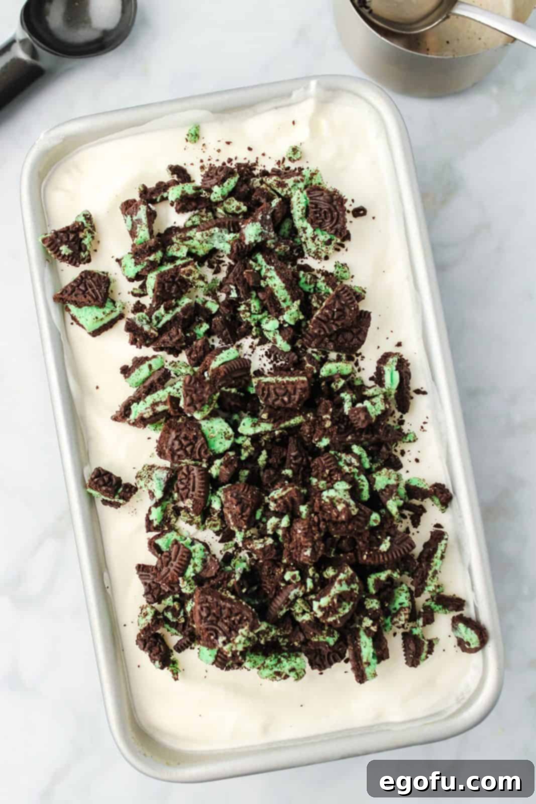 Mint cookies added to ice cream mixture in loaf pan