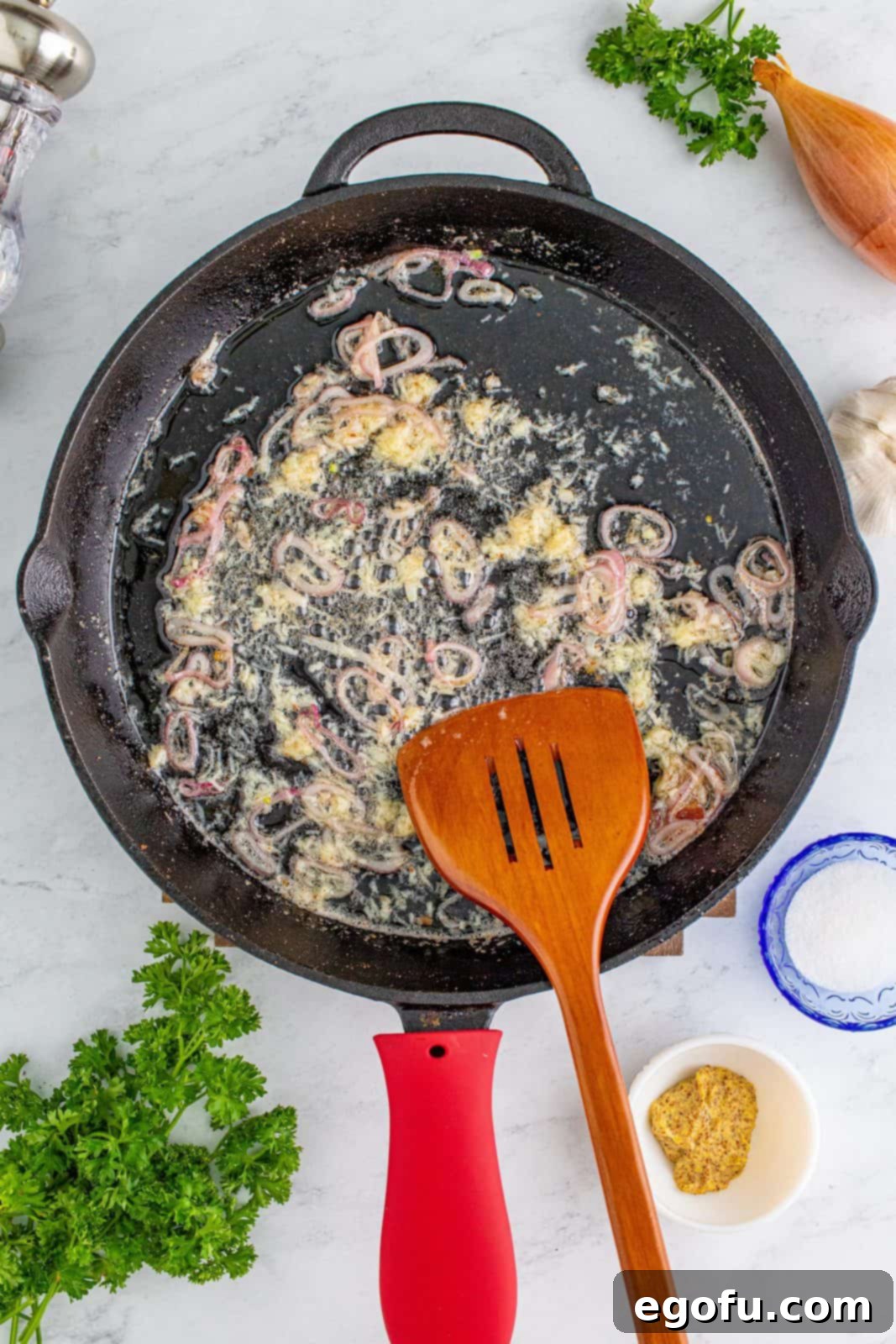 Hearty German Potato Salad 9 Minced garlic added to sautéed shallots in the skillet, being stirred to release its aroma.